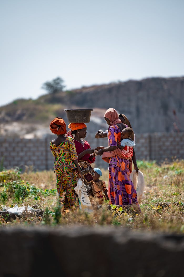 African women in traditional attire interacting outdoors in Deidei, Kaduna, Nigeria.